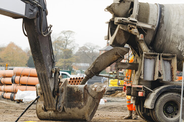 Discharging delivered concrete from mixer truck into excavator bucket