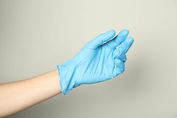Doctor in medical glove on light grey background, closeup