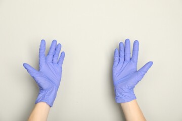 Doctor in medical gloves on light grey background, closeup