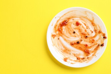 One dirty plate on yellow background, top view