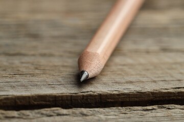 One sharp graphite pencil on wooden table, closeup