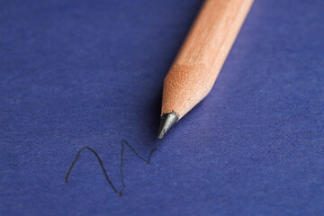 Drawing strokes with graphite pencil on blue background, closeup