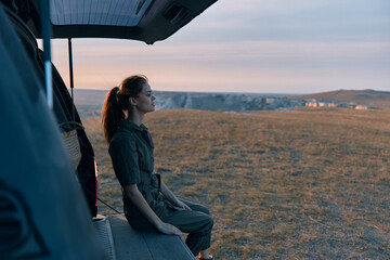 Woman sitting in van looking at sunset horizon on travel business trip beauty art adventure nature concept