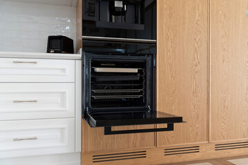 Built-in oven with open door in modern wooden kitchen