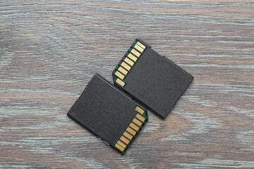 Two SD memory cards on grey wooden table, top view
