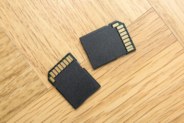 Two SD memory cards on light wooden table, top view