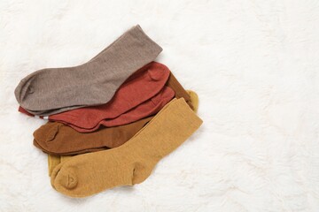 Different soft socks on white faux fur, top view. Space for text