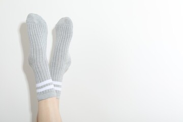 Woman in grey socks on light background, closeup. Space for text