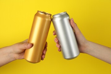 Women with tin cans on yellow background, closeup