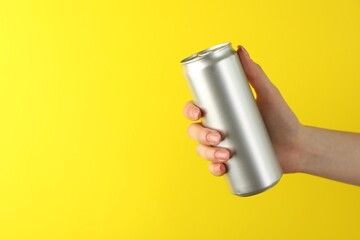 Woman with tin can on yellow background, closeup. Space for text