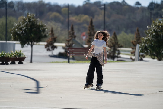 Young girl enjoying roller skating in urban park on sunny day
