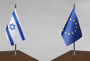 Tabletop flags of Israel and the European Union on stands on a gray blurred background