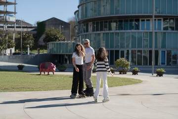 Father teaches daughters inline skating in city park