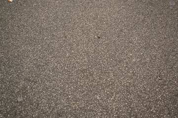Asphalt road texture background. Close-up of gray rough street surface for design, architecture, and 3D rendering projects. Grunge road material with small stones and grainy structure.