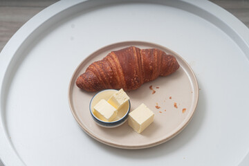 Large ruddy croissant on a plate on a white background