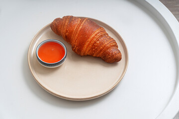 Large ruddy croissant on a plate on a white background