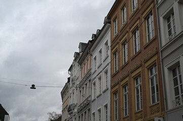 Baroque façade of a historic European building with ornate gold decorations, detailed sculptures, and tall windows. Elegant architecture captured on an overcast day, highlighting rich textures and cla