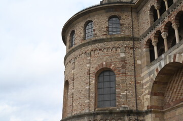 Old round stone tower with arched windows and brick facade. Historical European architecture detail against cloudy sky. Medieval building exterior for travel, history, and tourism concepts.