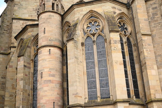 Gothic cathedral facade with tall stained glass windows and stone architecture. Historical European church building, detail of wall and arches. Travel and heritage concept.