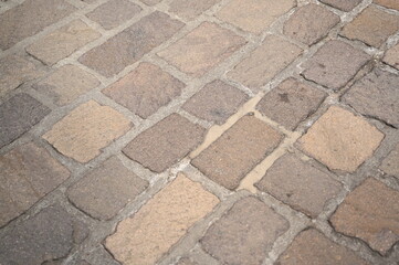 Old stone pavement with beige and brown cobblestones in a historic European city. Weathered texture background for architecture and travel concepts.