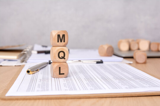 MQL acronym on wooden cubes placed on financial documents, concept of marketing qualified leads