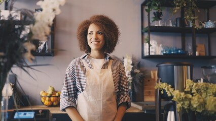 Friendly woman warmly greeting clients in her cozy coffee shop, welcoming attitude