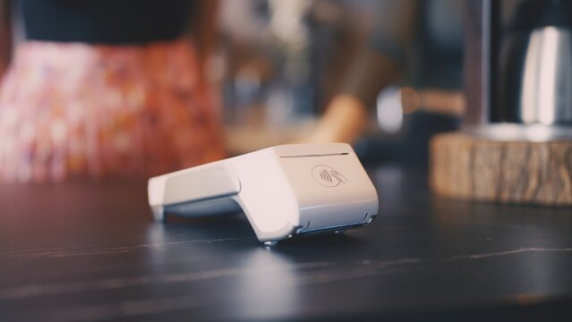 Card terminal on wooden counter in coffee shop, contactless payment system