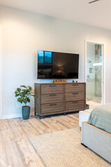A cozy bedroom with a stylish dresser and a wallmounted TV
