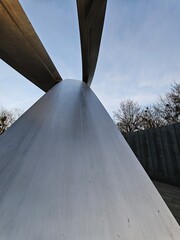 Upward view of monumental steel sculpture in Warsaw, captured from base to sky with dynamic lines and smooth texture, symbolizing remembrance and modern design.