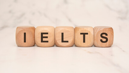 Wooden blocks with the word IELTS on a marble background