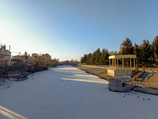 A view of a snow covered park with a gazebo in the background