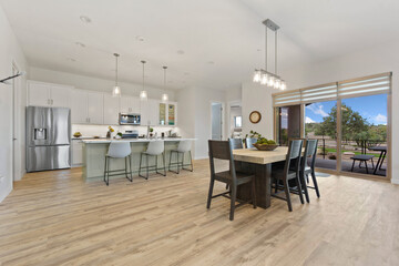 A kitchen with a table, chairs, and a stainless steel fridge