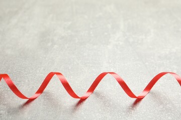 Shiny red serpentine streamer on grey background. Space for text