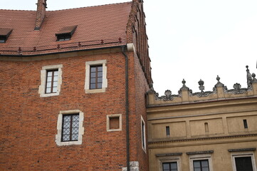 Historic brick building with decorative windows and roof details. Old European architecture with red brick walls and classic facade elements.