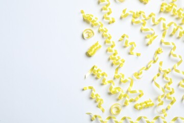 Yellow serpentine streamers on white background, top view