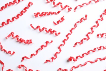 Red serpentine streamers on white background, top view