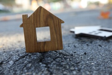 Wooden house model on cracked asphalt demonstrating earthquake disaster