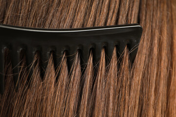 Brushing hair with plastic comb, closeup view