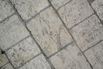 Obraz premium Natural stone wall texture with rectangular beige and gray blocks. Rough surface and organic patterns ideal for architectural backgrounds and design materials.