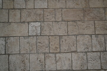 Stone wall and pavement texture with square and rectangular blocks. Rough aged surface of masonry used for construction, architecture, and design. Suitable for background, facade, or street pattern.