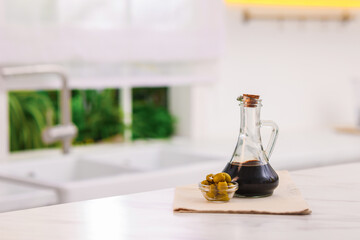 Balsamic vinegar and olives on table in kitchen. Space for text