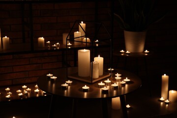 Many burning paraffin candles in dark room