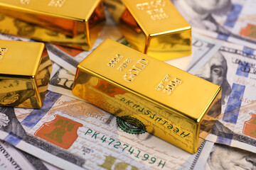 Shiny gold bars on dollar banknotes, closeup