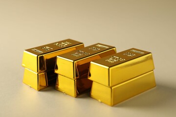 Shiny gold bars on beige background, closeup