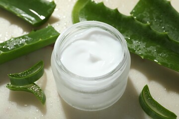 Cream and aloe leaves on light background, closeup