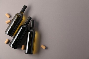 Naklejka premium Bottles of wine and corks on grey background, flat lay. Space for text