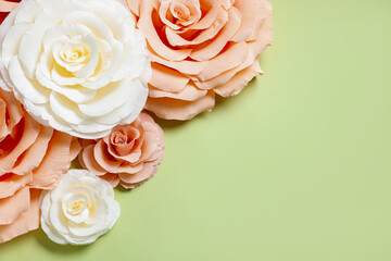 Beautiful paper flowers on light green background, flat lay. Space for text