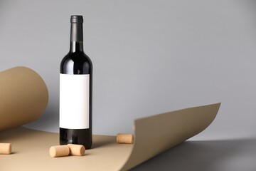 Bottle of wine with corks and paper on grey background. Space for text