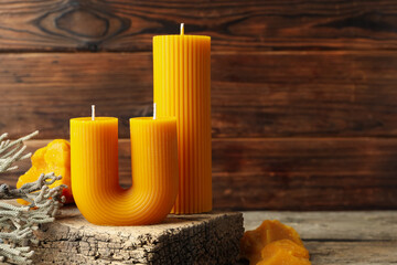 Beautiful beeswax candles and wax pieces on wooden table. Space for text