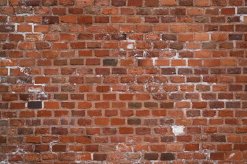 Obraz premium Old red brick wall texture with white efflorescence and weathered surface. Vintage masonry background for design, architecture, construction, and restoration projects. Rough textured red bricks with m